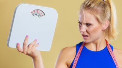 Fit fitness woman with scale. Frustrated angry blonde girl holding weight scales. Time for slimming weightloss diet and healthy lifestyles concept