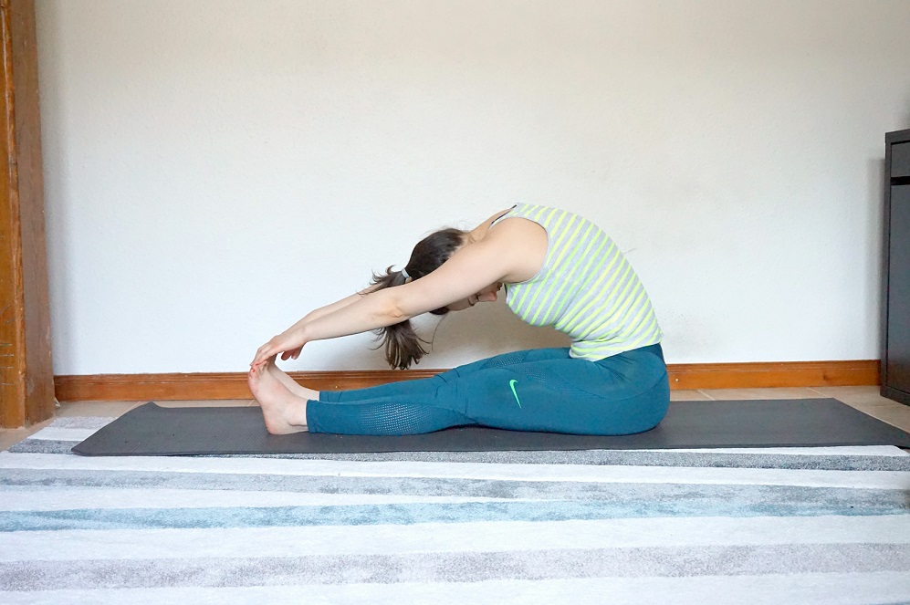 Girl demonstrating Seated forward fold yoga pose.