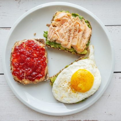 An avocado plus salmon toast, a peanut butter and jelly toast and and egg and an avocado wholewheat toast in a plate.