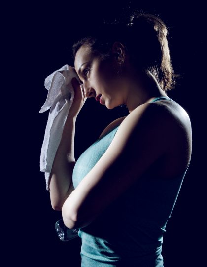 Fit girl wiping her sweat from her forehead with a towel from article 5 ways to Upgrade Your Home Workouts