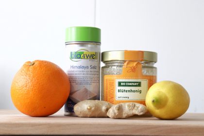 The ingredients needed for a homemade electrolyte drink - orange, lemon, ginger, honey and salt.