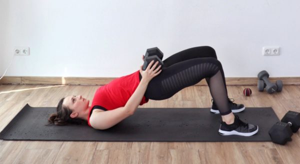 Glute bridge with a dumbbell part of an at-home dumbbell workout