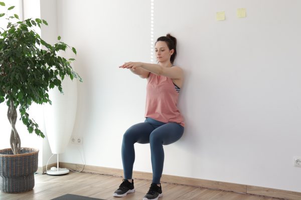 Wallsit bodyweight exercise demonstration by a young woman. 