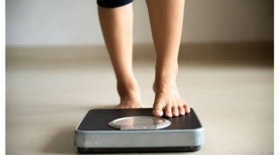 woman stepping on a scale after defying weight loss myths