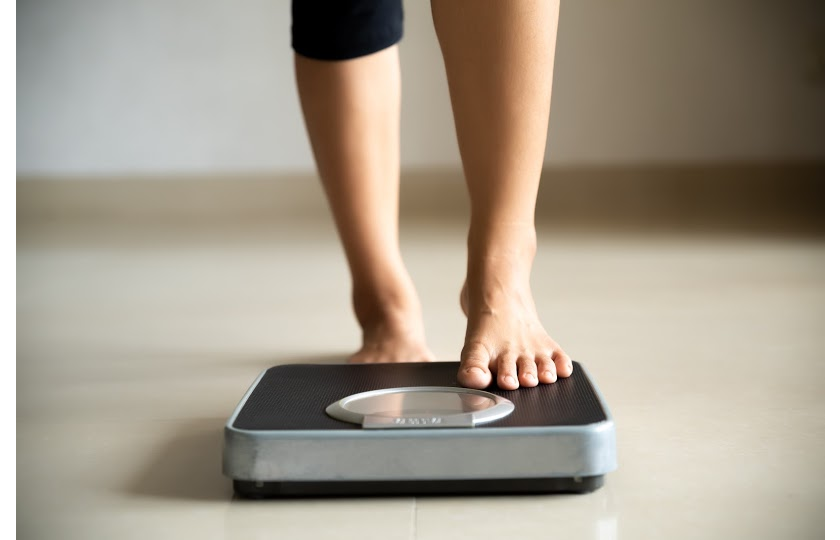 woman stepping on a scale after defying weight loss myths
